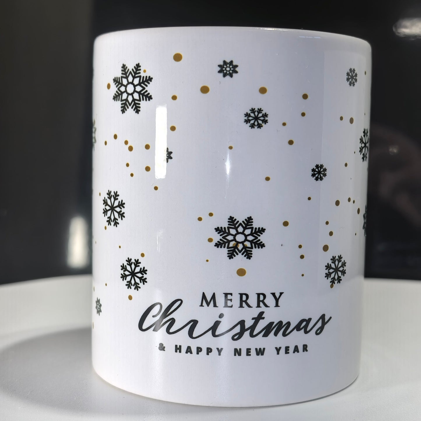 Seite der Weihnachtstasse Schwarz Gold mit "Merry Christmas & Happy New Year"-Schriftzug und Schneeflocken.