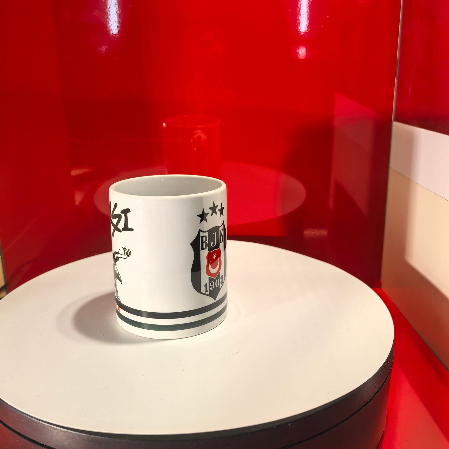 Weiße Beşiktaş-Tasse mit dem ikonischen Çarşı-Schriftzug und einem schwarzen Adler-Motiv.