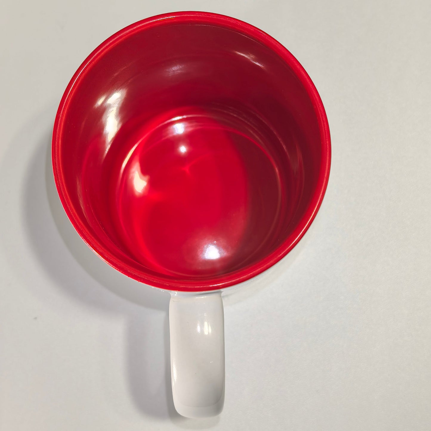 Blick in das Innere der Weihnachtstasse mit leuchtend rotem Finish und klarem Henkel.