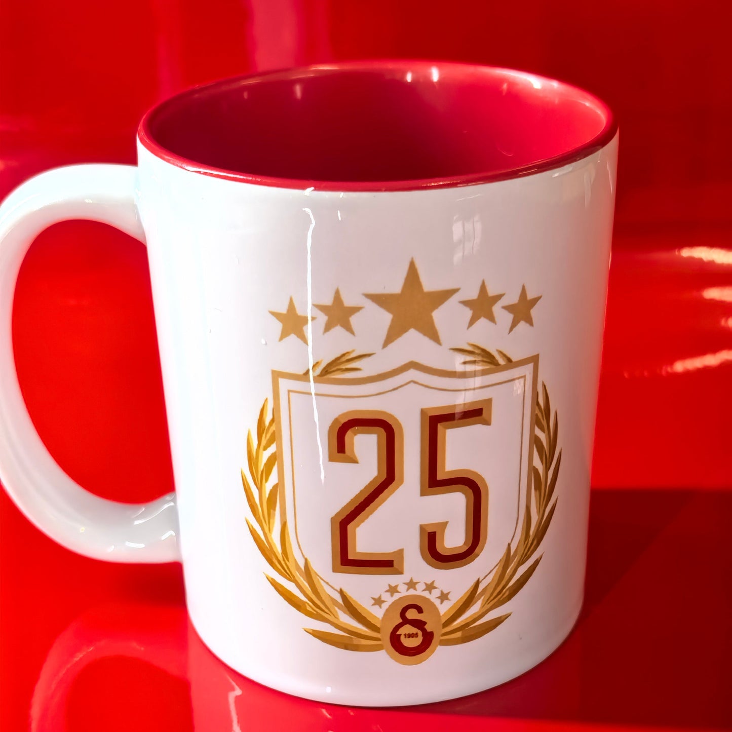 Wappen mit der Zahl "25", Lorbeerzweige, Sterne, GS-Emblem unten.