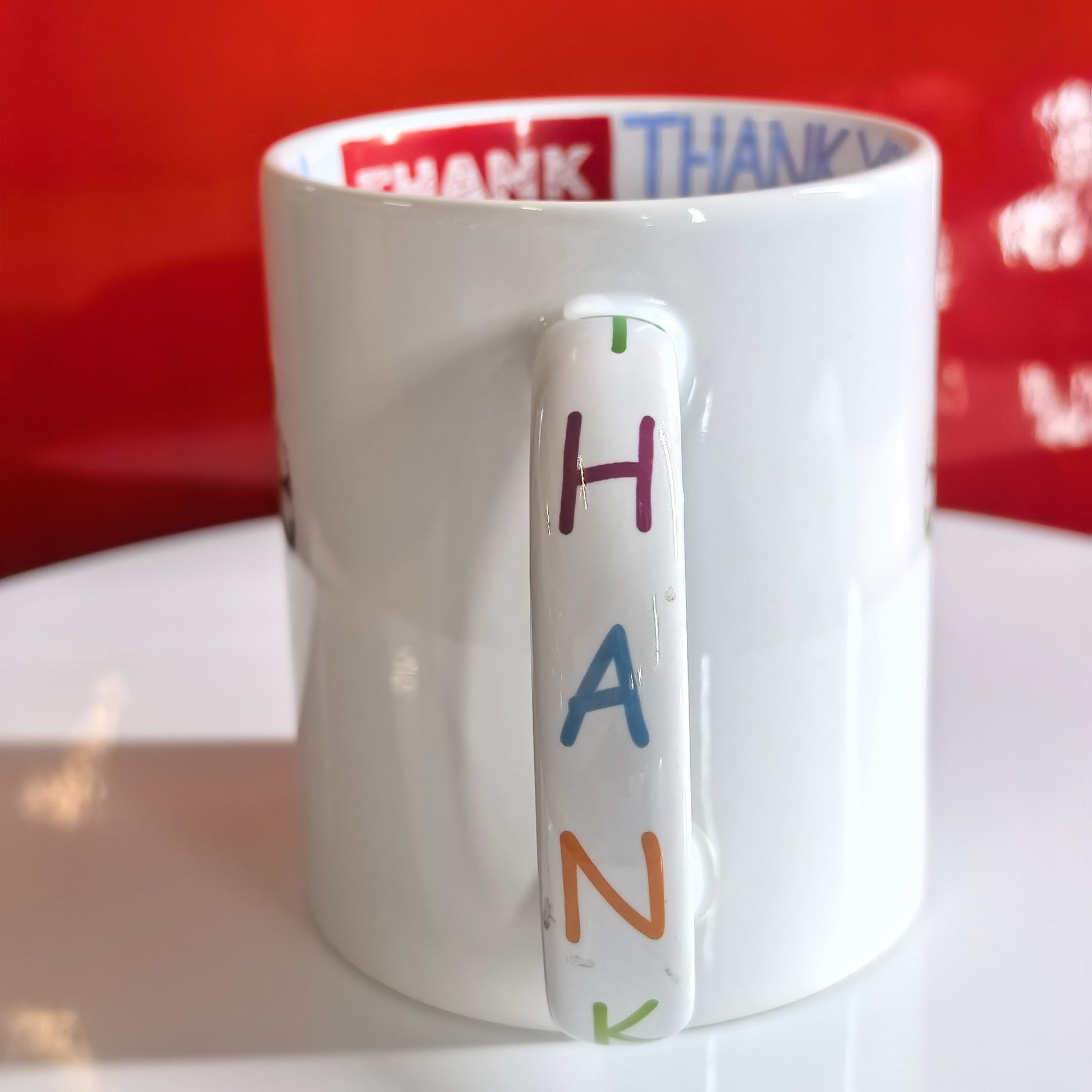 Henkel der Personalisierten Tasse mit bunten "THANK"-Buchstaben.