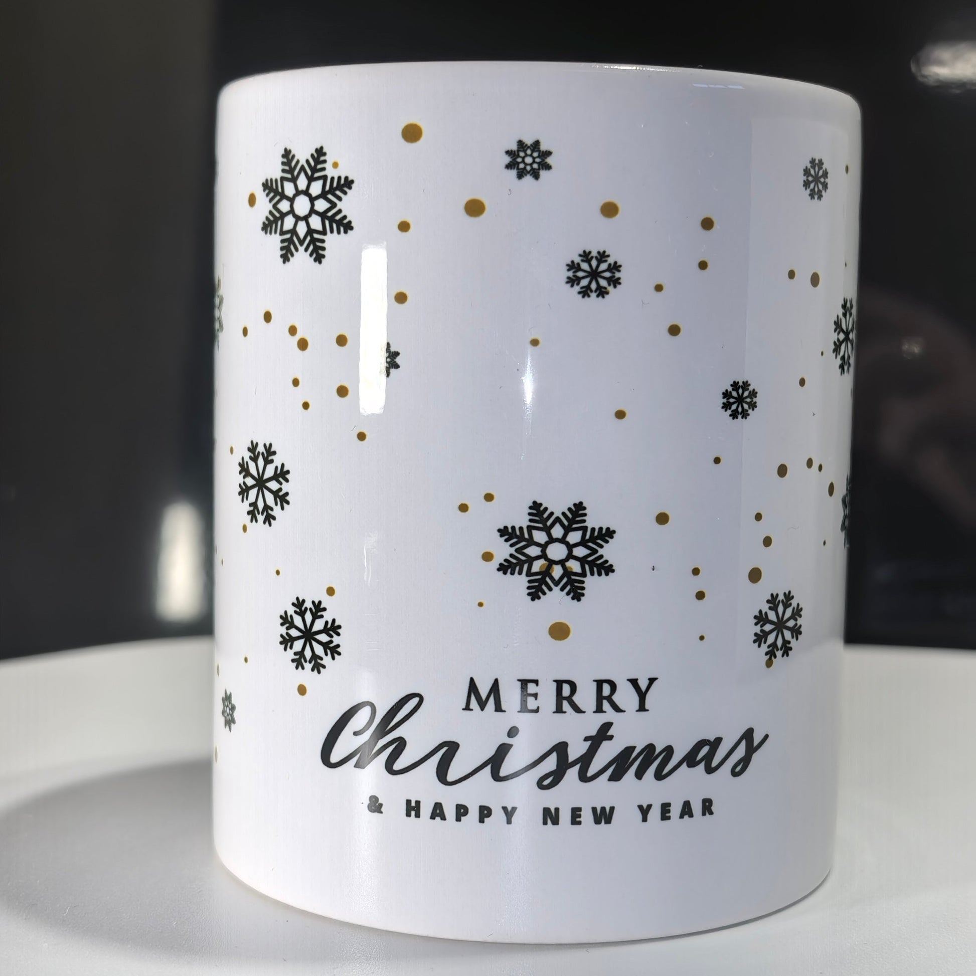Seite der Weihnachtstasse Schwarz Gold mit "Merry Christmas & Happy New Year"-Schriftzug und Schneeflocken.