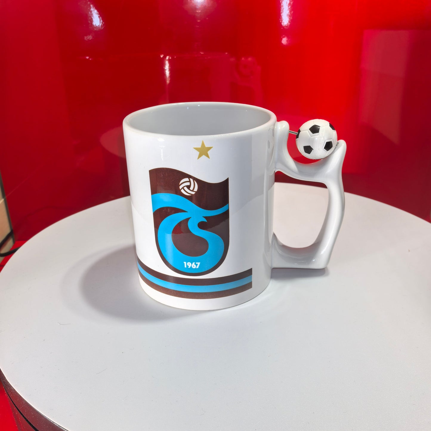 Weiße Trabzonspor Fan-Tasse mit offiziellem Vereinslogo (Bordo-Mavi) und Fußball-Detail am Henkel.