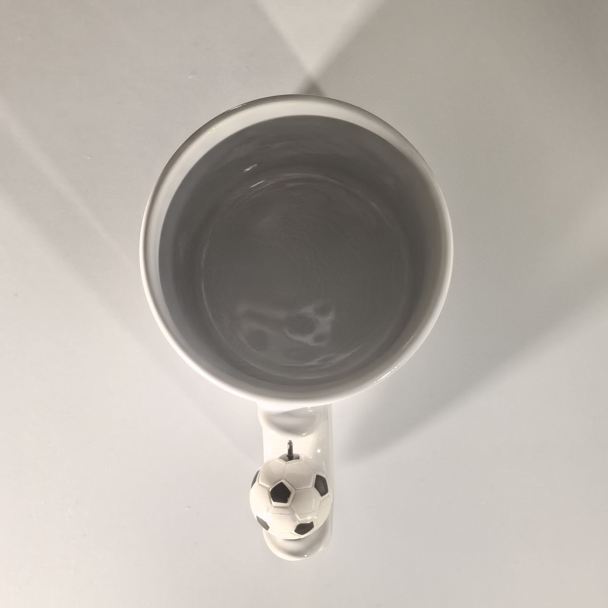 Blick in die graue Innenseite der Fußball Tasse mit Fußball-Henkel.